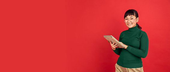 Image showing East asian woman\'s portrait isolated on red studio background with copyspace