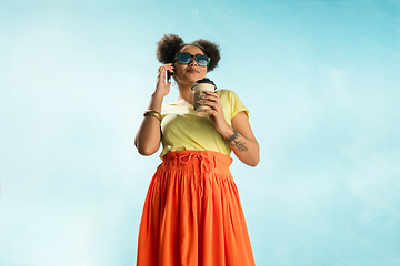 Image showing Portrait of female fashion model on blue sky background. Style and beauty concept, bright appearance