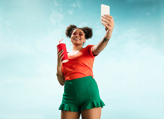 Image showing Portrait of female fashion model on blue sky background. Style and beauty concept, bright appearance