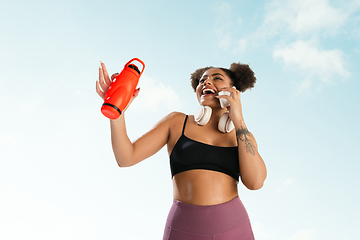 Image showing Portrait of female fashion model on blue sky background. Style and beauty concept, bright appearance. Lifestyle sport.