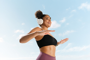 Image showing Portrait of female fashion model on blue sky background. Style and beauty concept, bright appearance. Lifestyle sport.