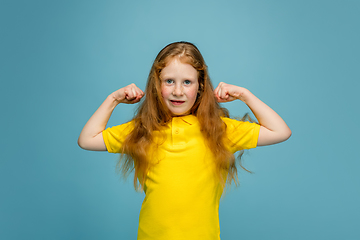 Image showing Happy redhair girl isolated on blue studio background. Looks happy, cheerful, sincere. Copyspace. Childhood, education, emotions concept