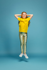 Image showing Happy redhair girl isolated on blue studio background. Looks happy, cheerful, sincere. Copyspace. Childhood, education, emotions concept