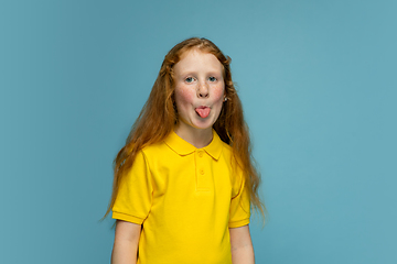 Image showing Happy redhair girl isolated on blue studio background. Looks happy, cheerful, sincere. Copyspace. Childhood, education, emotions concept