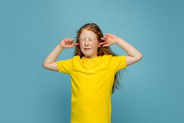 Image showing Happy redhair girl isolated on blue studio background. Looks happy, cheerful, sincere. Copyspace. Childhood, education, emotions concept