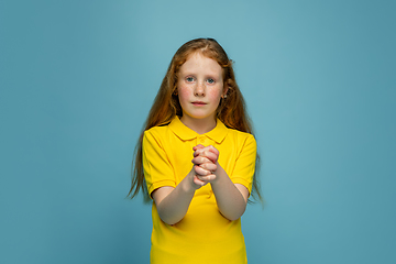 Image showing Happy redhair girl isolated on blue studio background. Looks happy, cheerful, sincere. Copyspace. Childhood, education, emotions concept