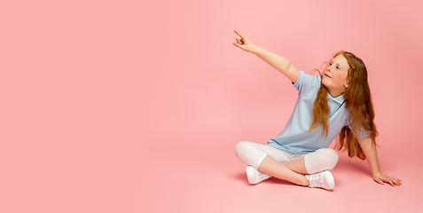 Image showing Happy redhair girl isolated on pink studio background. Looks happy, cheerful, sincere. Copyspace. Childhood, education, emotions concept