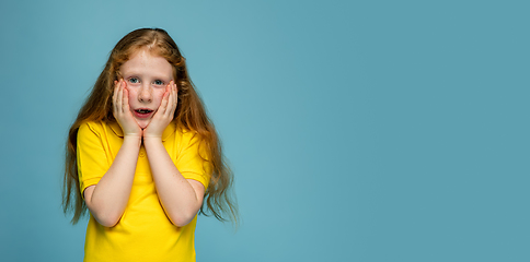 Image showing Happy redhair girl isolated on blue studio background. Looks happy, cheerful, sincere. Copyspace. Childhood, education, emotions concept