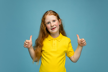 Image showing Happy redhair girl isolated on blue studio background. Looks happy, cheerful, sincere. Copyspace. Childhood, education, emotions concept