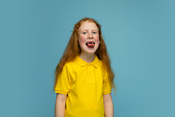 Image showing Happy redhair girl isolated on blue studio background. Looks happy, cheerful, sincere. Copyspace. Childhood, education, emotions concept