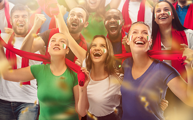 Image showing Italian football, soccer fans cheering their team with a red scarfs at stadium. Excited fans cheering a goal, supporting favourite players