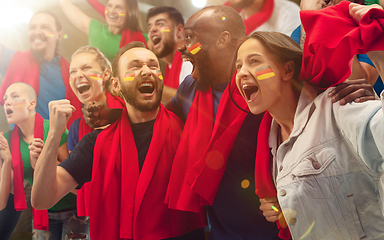 Image showing German football, soccer fans cheering their team with a red scarfs at stadium. Excited fans cheering a goal, supporting favourite players