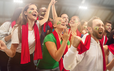 Image showing Brazilian football, soccer fans cheering their team with a red scarfs at stadium. Excited fans cheering a goal, supporting favourite players