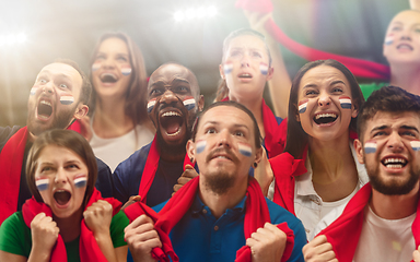 Image showing Netherlands football, soccer fans cheering their team with a red scarfs at stadium. Excited fans cheering a goal, supporting favourite players