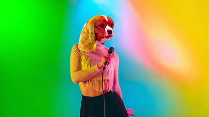 Image showing Talented dog, professional musician performing on multicoloted background in neon light. Concept of music, hobby, festival, contemporary art collage. Modern design.