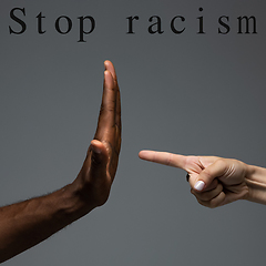 Image showing African and caucasian hands gesturing on gray studio background, tolerance and equality concept