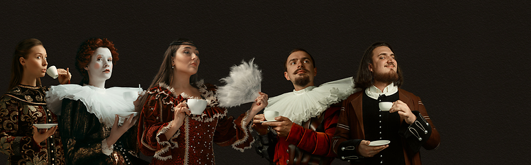 Image showing Medieval people as a royalty persons in vintage clothing on dark background. Concept of comparison of eras, modernity and renaissance, baroque style.