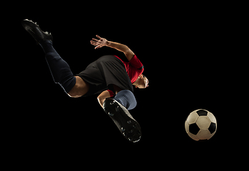 Image showing Young caucasian football, soccer player in action, motion isolated on black background, look from the bottom. Concept of sport, movement, energy and dynamic.