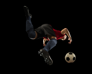 Image showing Young caucasian football, soccer player in action, motion isolated on black background, look from the bottom. Concept of sport, movement, energy and dynamic.