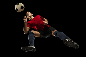 Image showing Young caucasian football, soccer player in action, motion isolated on black background, look from the bottom. Concept of sport, movement, energy and dynamic.