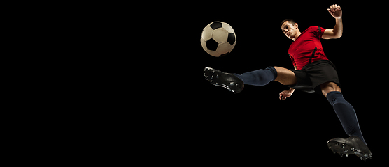 Image showing Young caucasian football, soccer player in action, motion isolated on black background, look from the bottom. Concept of sport, movement, energy and dynamic.