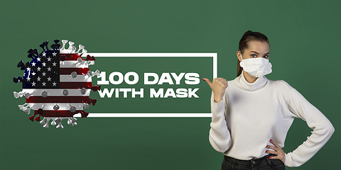 Image showing Woman in protective face mask isolated on green studio background. New rules of COVID spreading prevention