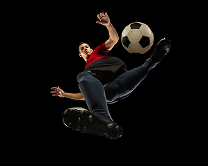 Image showing Young caucasian football, soccer player in action, motion isolated on black background, look from the bottom. Concept of sport, movement, energy and dynamic.