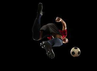 Image showing Young caucasian football, soccer player in action, motion isolated on black background, look from the bottom. Concept of sport, movement, energy and dynamic.