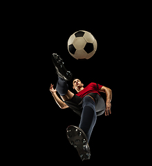 Image showing Young caucasian football, soccer player in action, motion isolated on black background, look from the bottom. Concept of sport, movement, energy and dynamic.