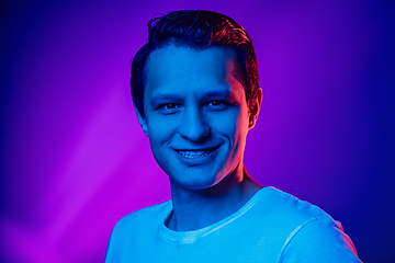 Image showing Caucasian man\'s portrait isolated on purple blue studio background in multicolored neon light