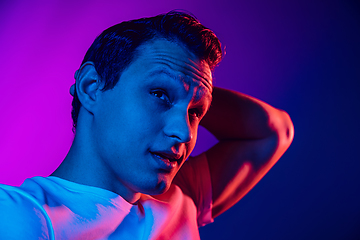 Image showing Caucasian man\'s portrait isolated on purple blue studio background in multicolored neon light