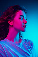 Image showing Caucasian woman\'s portrait isolated on blue studio background in multicolored neon light