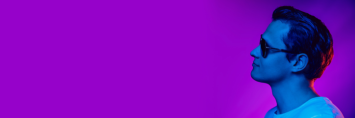 Image showing Caucasian man\'s portrait isolated on purple blue studio background in multicolored neon light