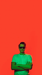 Image showing Caucasian man\'s portrait isolated on red studio background in multicolored neon light