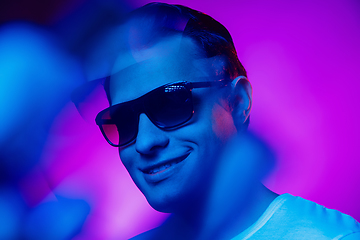 Image showing Caucasian man\'s portrait isolated on purple blue studio background in multicolored neon light