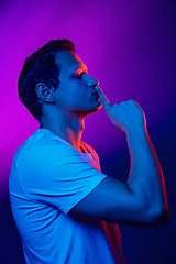 Image showing Caucasian man\'s portrait isolated on purple blue studio background in multicolored neon light