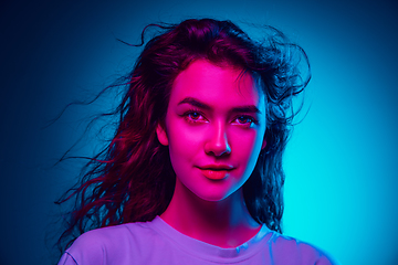 Image showing Caucasian woman\'s portrait isolated on blue studio background in multicolored neon light