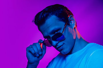 Image showing Caucasian man\'s portrait isolated on purple blue studio background in multicolored neon light