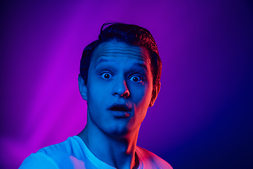 Image showing Caucasian man\'s portrait isolated on purple blue studio background in multicolored neon light