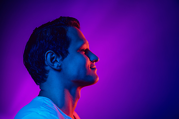 Image showing Caucasian man\'s portrait isolated on purple blue studio background in multicolored neon light