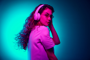 Image showing Caucasian woman\'s portrait isolated on blue studio background in multicolored neon light