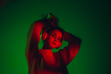 Image showing Caucasian woman\'s portrait isolated on green studio background in multicolored neon light