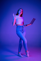 Image showing Caucasian woman\'s portrait isolated on blue studio background in multicolored neon light