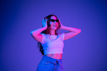 Image showing Caucasian woman\'s portrait isolated on blue studio background in multicolored neon light