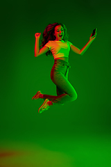 Image showing Caucasian woman\'s portrait isolated on green studio background in multicolored neon light