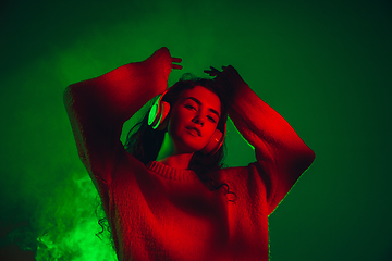 Image showing Caucasian woman\'s portrait isolated on green studio background in multicolored neon light