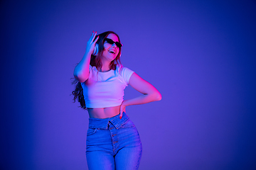 Image showing Caucasian woman\'s portrait isolated on blue studio background in multicolored neon light