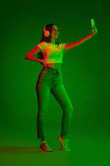 Image showing Caucasian woman\'s portrait isolated on green studio background in multicolored neon light