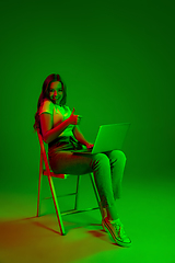 Image showing Caucasian woman\'s portrait isolated on green studio background in multicolored neon light