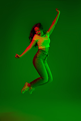 Image showing Caucasian woman\'s portrait isolated on green studio background in multicolored neon light